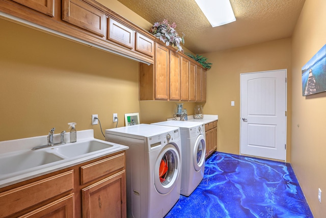 clothes washing area with cabinet space, a sink, a textured ceiling, and washing machine and clothes dryer