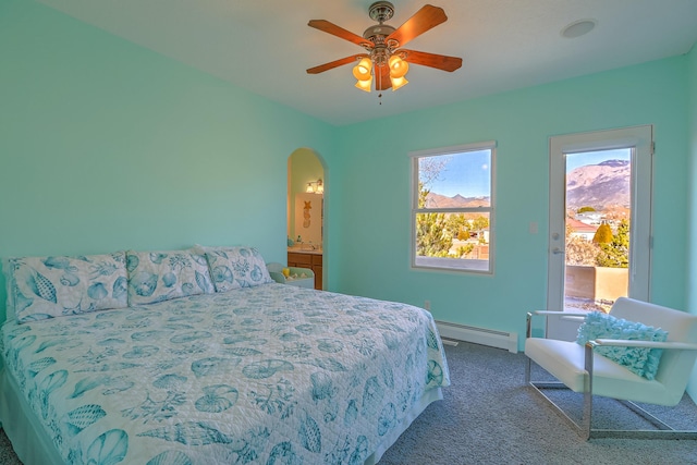 carpeted bedroom featuring baseboards, arched walkways, baseboard heating, and a ceiling fan