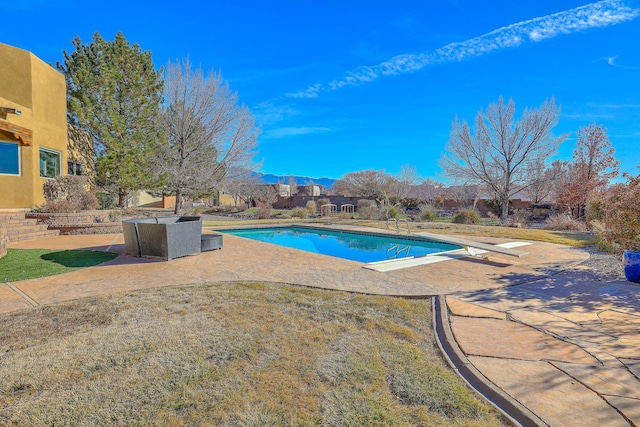 view of swimming pool with a yard, a patio, and a diving board