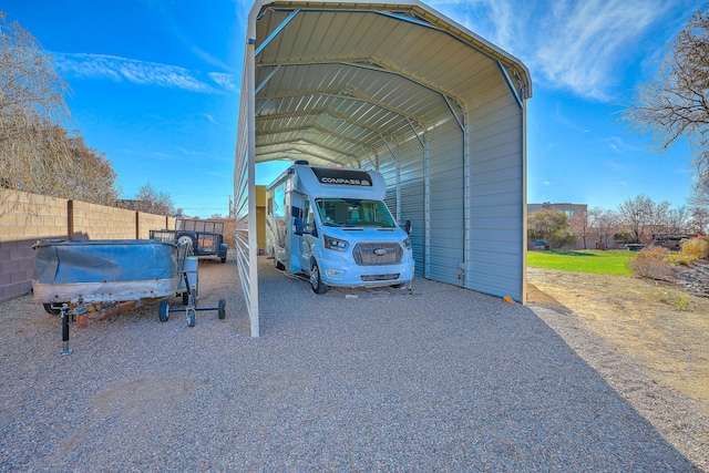 view of parking featuring a carport, gravel driveway, and fence