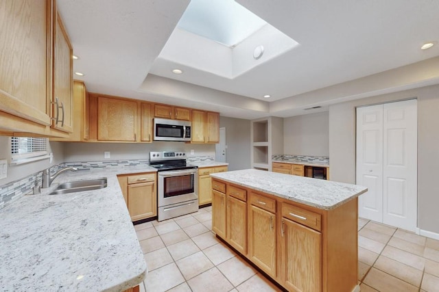 kitchen with light stone countertops, sink, stainless steel appliances, a kitchen island, and light tile patterned flooring