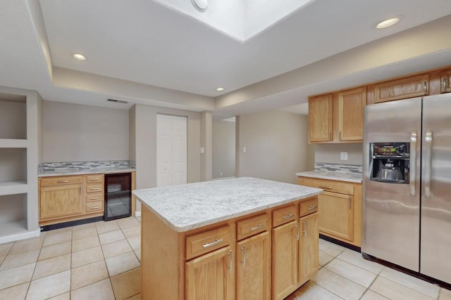 kitchen featuring a center island, stainless steel fridge, light tile patterned floors, and beverage cooler