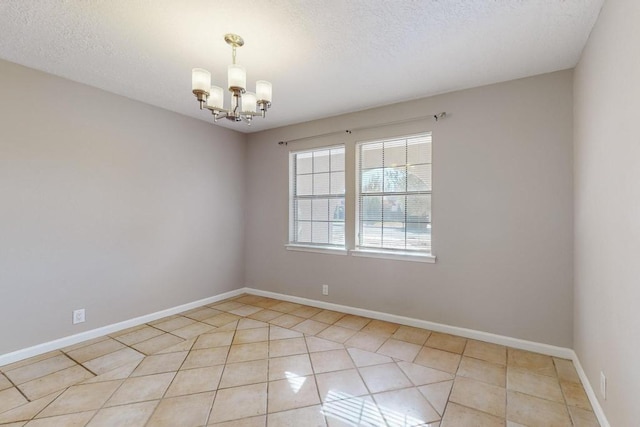 tiled empty room with a notable chandelier and a textured ceiling