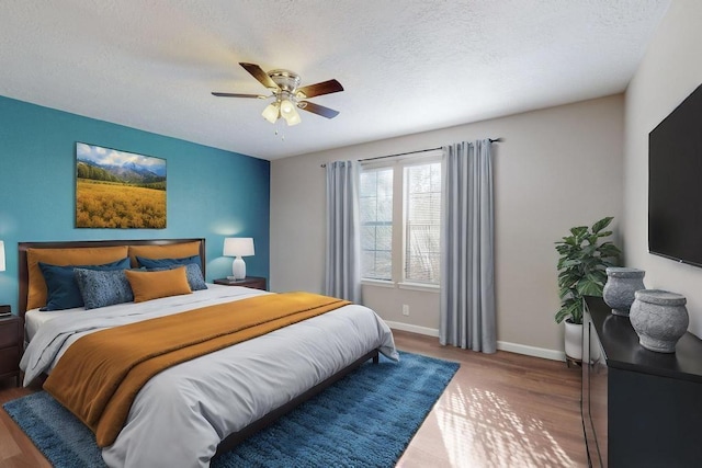 bedroom with ceiling fan, hardwood / wood-style floors, and a textured ceiling