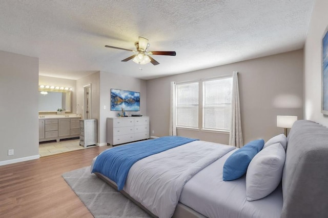 bedroom with ensuite bath, ceiling fan, light hardwood / wood-style floors, and a textured ceiling