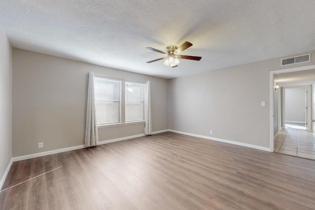 empty room featuring hardwood / wood-style flooring, ceiling fan, and a textured ceiling