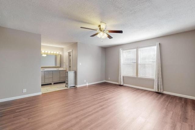 unfurnished bedroom featuring a textured ceiling, ceiling fan, light hardwood / wood-style floors, and ensuite bathroom