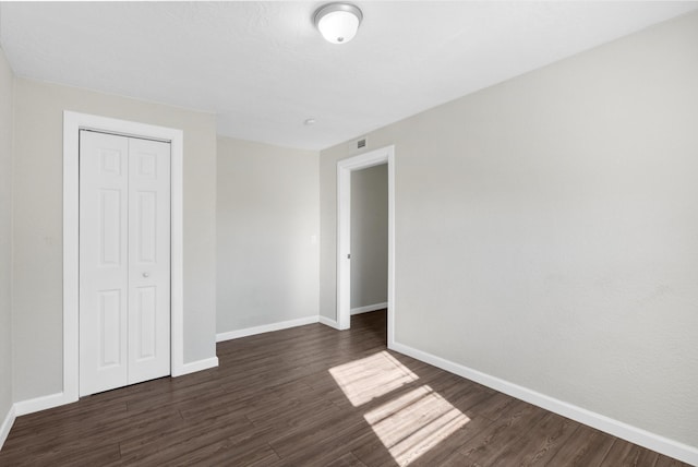 unfurnished bedroom featuring dark hardwood / wood-style flooring and a closet