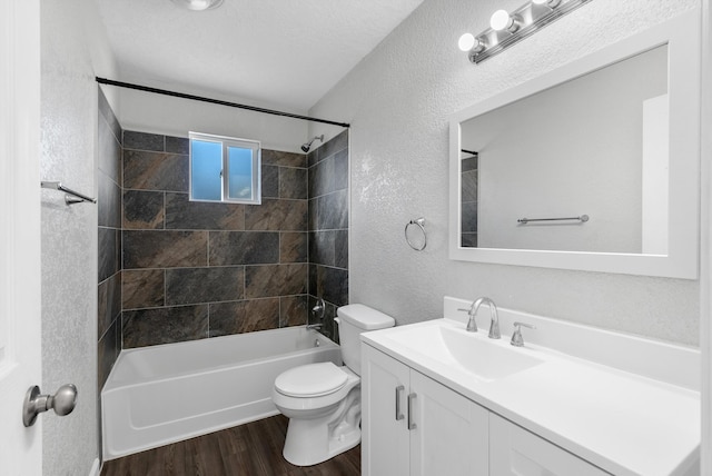 full bathroom featuring vanity, hardwood / wood-style flooring, tiled shower / bath combo, toilet, and a textured ceiling