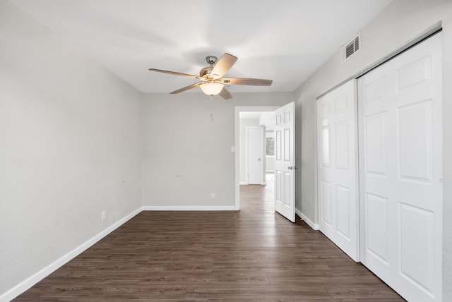 unfurnished bedroom with ceiling fan, dark wood-type flooring, and a closet