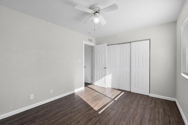 unfurnished bedroom with ceiling fan, a closet, and dark wood-type flooring