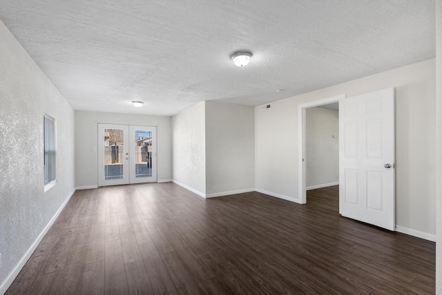 empty room with a textured ceiling, french doors, and dark hardwood / wood-style floors