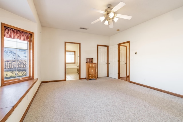 unfurnished bedroom featuring ceiling fan, ensuite bathroom, light carpet, and multiple windows