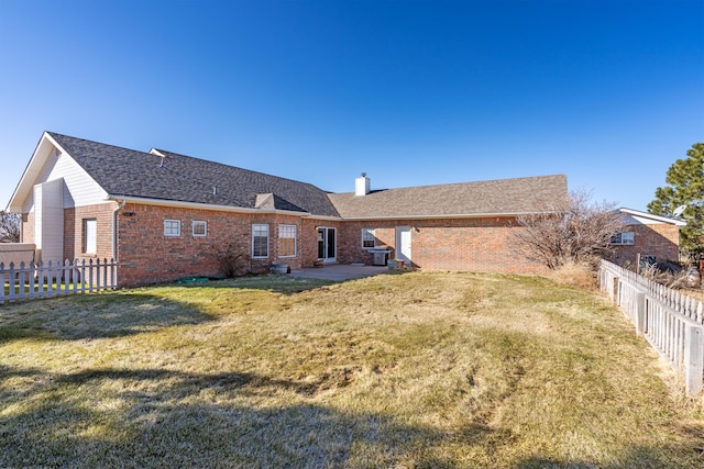 rear view of house featuring a lawn, central AC, and a patio