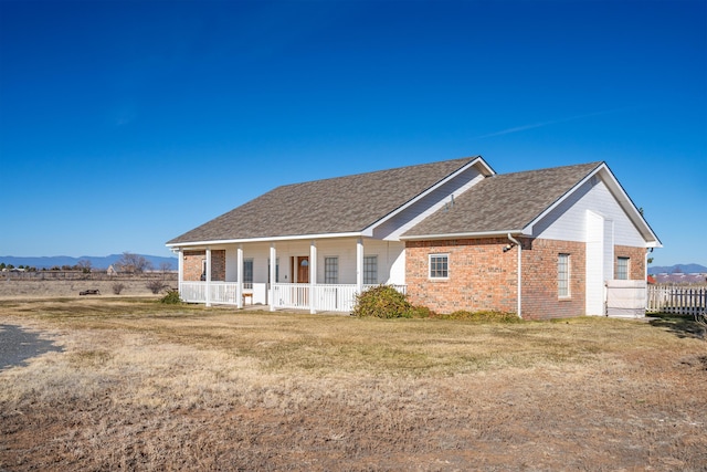 view of front of property featuring covered porch, a mountain view, and a front lawn