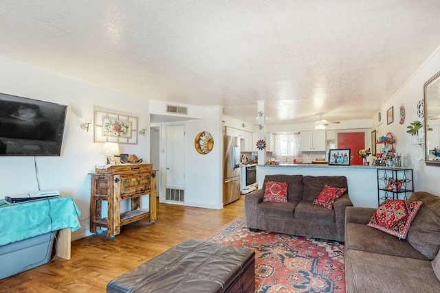 living room with ceiling fan, light hardwood / wood-style floors, and a textured ceiling