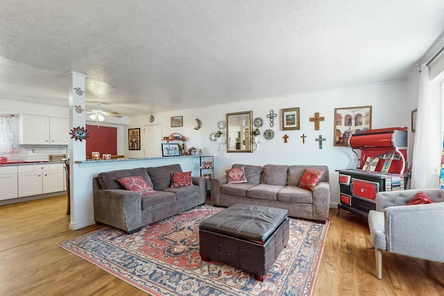 living room featuring ceiling fan, light hardwood / wood-style floors, and a textured ceiling