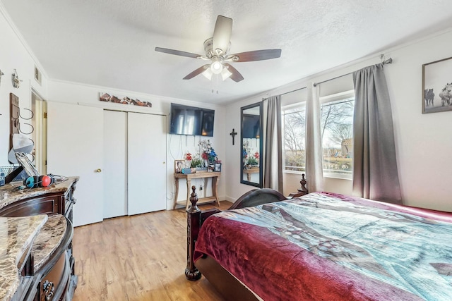 bedroom with a textured ceiling, light hardwood / wood-style flooring, ceiling fan, and ornamental molding