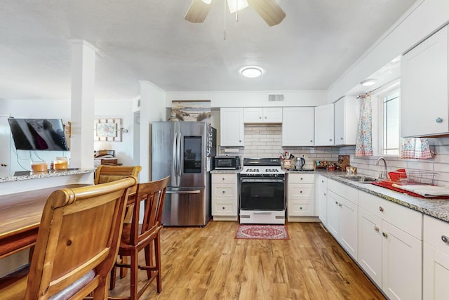 kitchen featuring decorative backsplash, appliances with stainless steel finishes, light stone counters, sink, and white cabinets