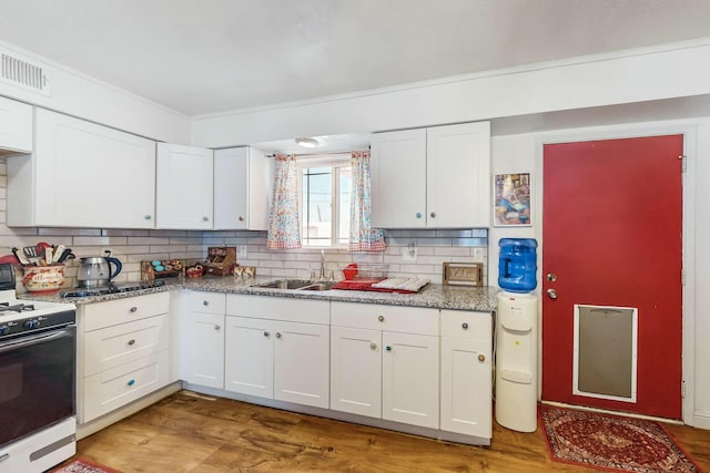 kitchen featuring light stone countertops, tasteful backsplash, white range, sink, and white cabinets