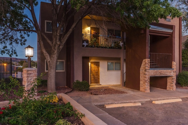 view of front of house featuring an outdoor stone fireplace and a balcony