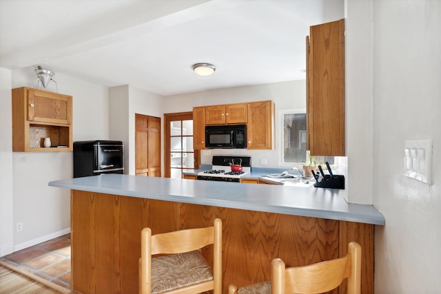 kitchen with kitchen peninsula, a breakfast bar, and white range with gas stovetop