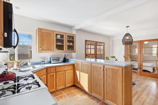 kitchen featuring decorative light fixtures, a healthy amount of sunlight, kitchen peninsula, and sink