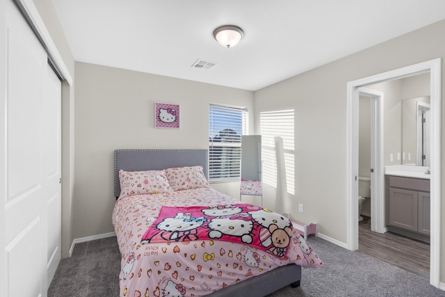 carpeted bedroom featuring ensuite bathroom and a closet