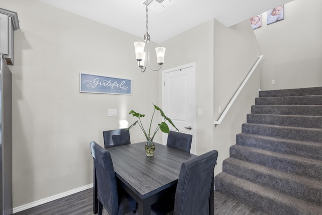 dining space with dark hardwood / wood-style floors and an inviting chandelier