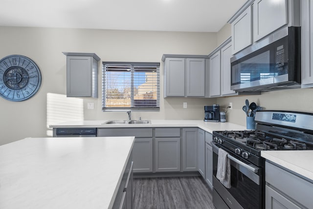 kitchen featuring appliances with stainless steel finishes, gray cabinetry, dark wood-type flooring, and sink