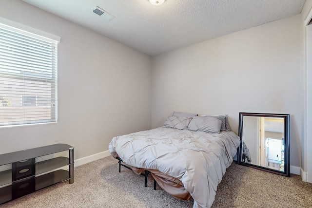 bedroom featuring a textured ceiling, light carpet, and multiple windows