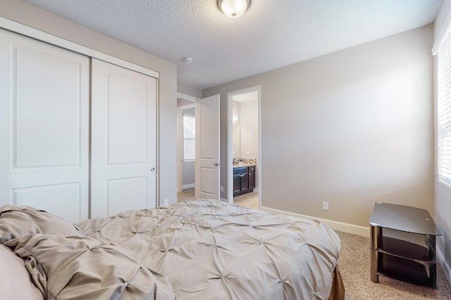 bedroom with connected bathroom, light carpet, a closet, and a textured ceiling