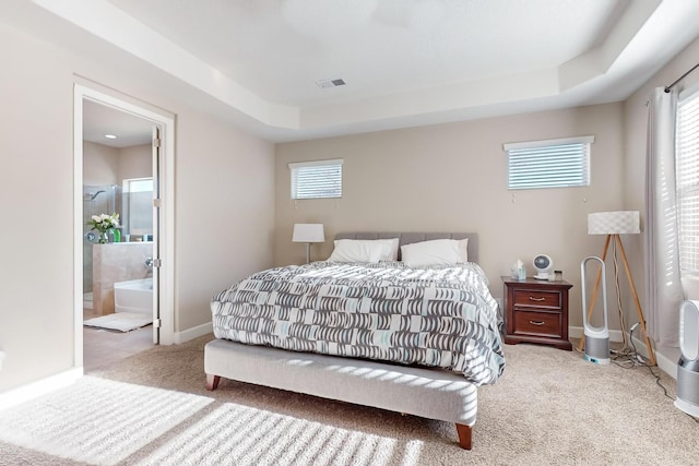 carpeted bedroom featuring connected bathroom and a tray ceiling