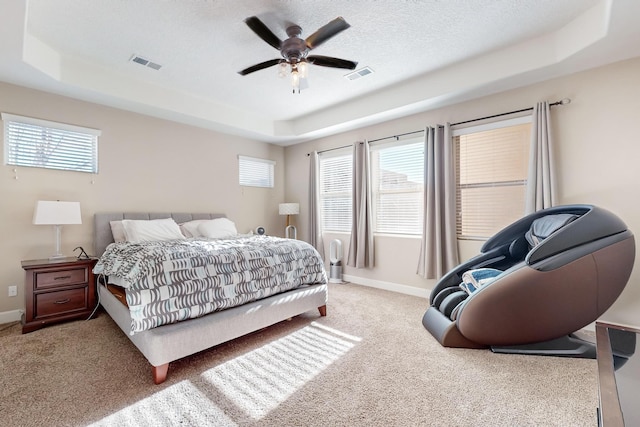 bedroom featuring multiple windows, a tray ceiling, and ceiling fan