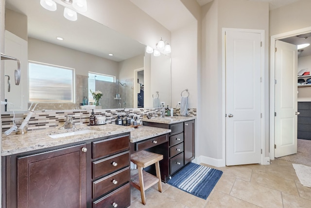 bathroom featuring tile patterned floors, vanity, a shower with shower door, and backsplash