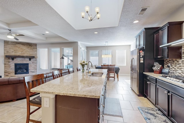 kitchen with a kitchen bar, a kitchen island with sink, hanging light fixtures, and sink