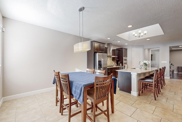 tiled dining space featuring a skylight, sink, a textured ceiling, and an inviting chandelier