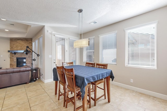 dining room with a fireplace, light tile patterned floors, and a textured ceiling