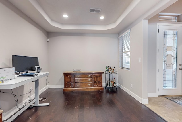 home office with dark hardwood / wood-style floors and a raised ceiling