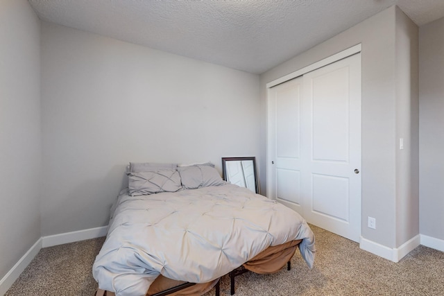 carpeted bedroom with a textured ceiling and a closet