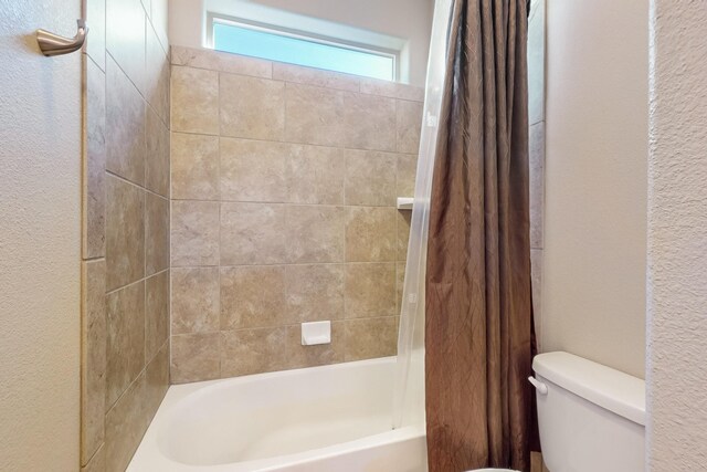 bathroom featuring shower / bath combination with curtain and toilet