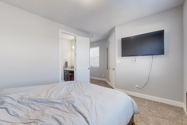 carpeted bedroom with a textured ceiling and connected bathroom