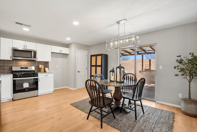 dining room featuring light wood-type flooring and an inviting chandelier