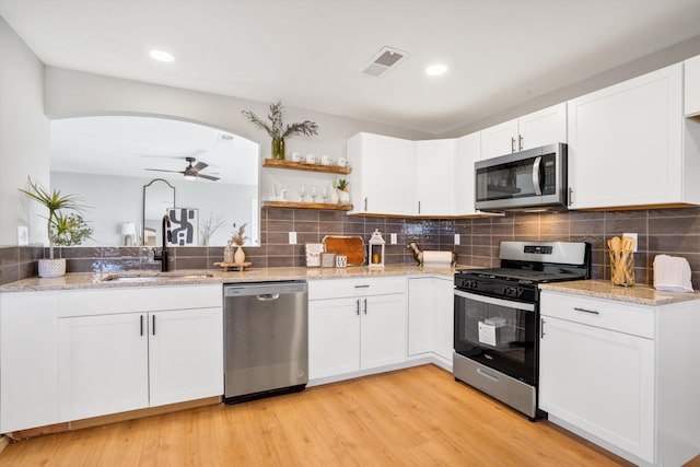 kitchen with ceiling fan, sink, stainless steel appliances, white cabinets, and light wood-type flooring