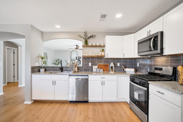 kitchen with white cabinets, sink, appliances with stainless steel finishes, and light hardwood / wood-style flooring