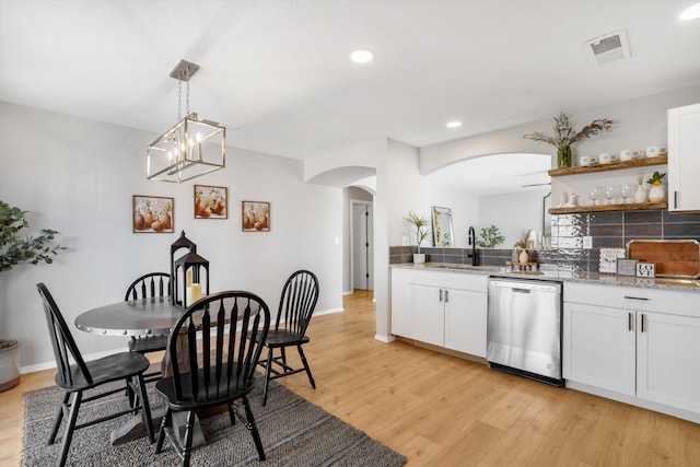 dining space featuring a chandelier, sink, and light hardwood / wood-style flooring