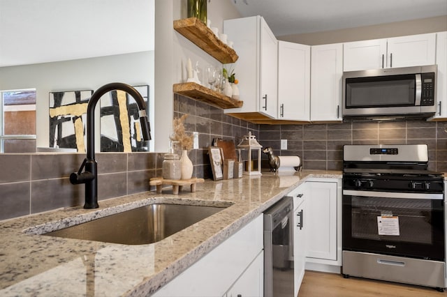 kitchen featuring white cabinetry, light stone countertops, sink, light hardwood / wood-style floors, and appliances with stainless steel finishes