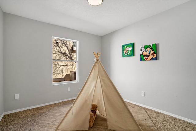 recreation room featuring carpet flooring and a textured ceiling