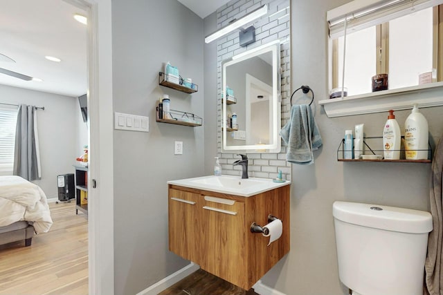 bathroom with decorative backsplash, vanity, wood-type flooring, and toilet