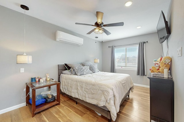 bedroom with a wall unit AC, ceiling fan, and wood-type flooring